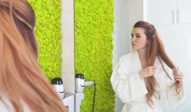 Modern banyo aynaya bakarak ve saçlarını kontrol genç kadın