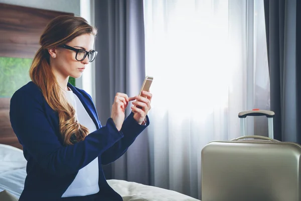 Femme d'affaires avec valise dans une chambre d'hôtel moderne avec ordinateur portable et smartphone — Photo