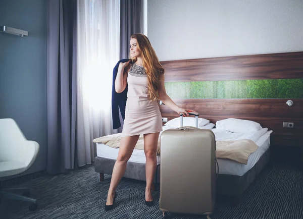 Zakenvrouw met koffer in een moderne hotelkamer — Stockfoto