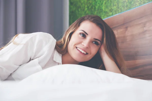 Jolie femme au lit dans un appartement moderne souriant après le réveil — Photo