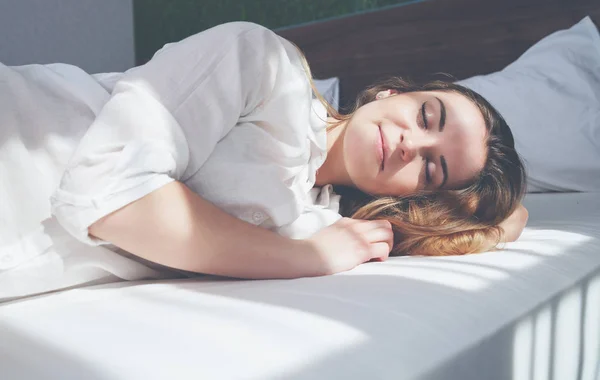 Красавица на кровати в современной квартире улыбается после пробуждения — стоковое фото