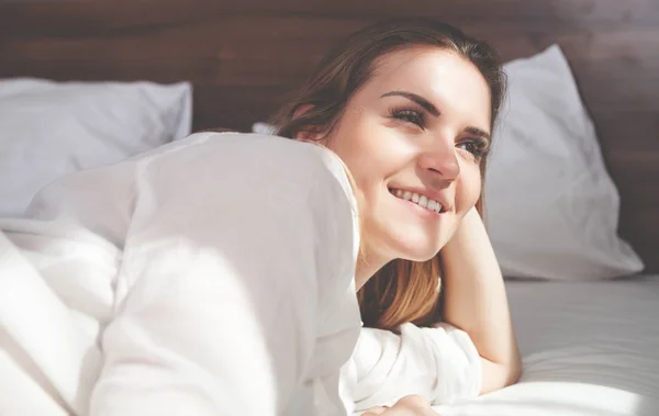 Jolie femme au lit dans un appartement moderne souriant après le réveil — Photo