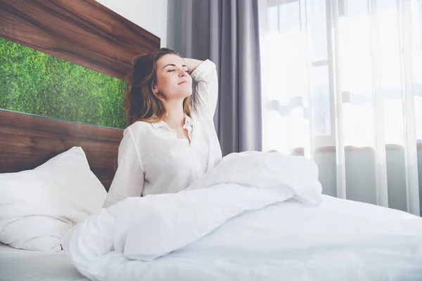 Mooie vrouw op bed in modern appartement glimlachend en stretching na wake up — Stockfoto