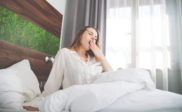 Hübsche Frau gähnt nach dem Aufwachen im Bett in moderner Wohnung — Stockfoto