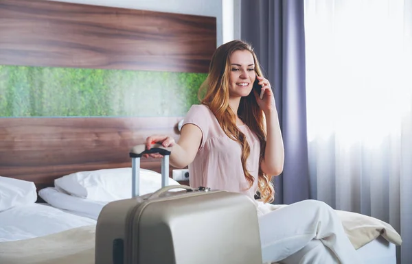 電話を使用してモダンなホテルのアパートでスーツケースときれいな女性 — ストック写真