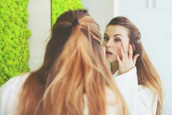 Mujer bonita mirando el espejo en el baño moderno —  Fotos de Stock