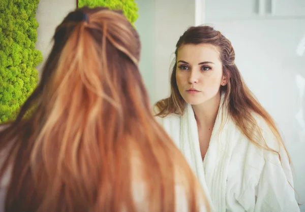 Hübsche Frau blickt in modernem Badezimmer auf Spiegel — Stockfoto