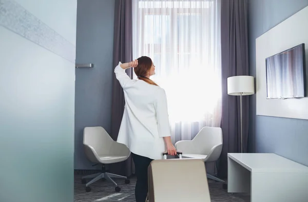 Mulher puxando mala no quarto de hotel moderno — Fotografia de Stock