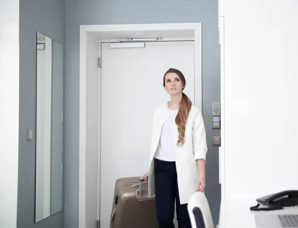 Mulher puxando mala no quarto de hotel moderno — Fotografia de Stock