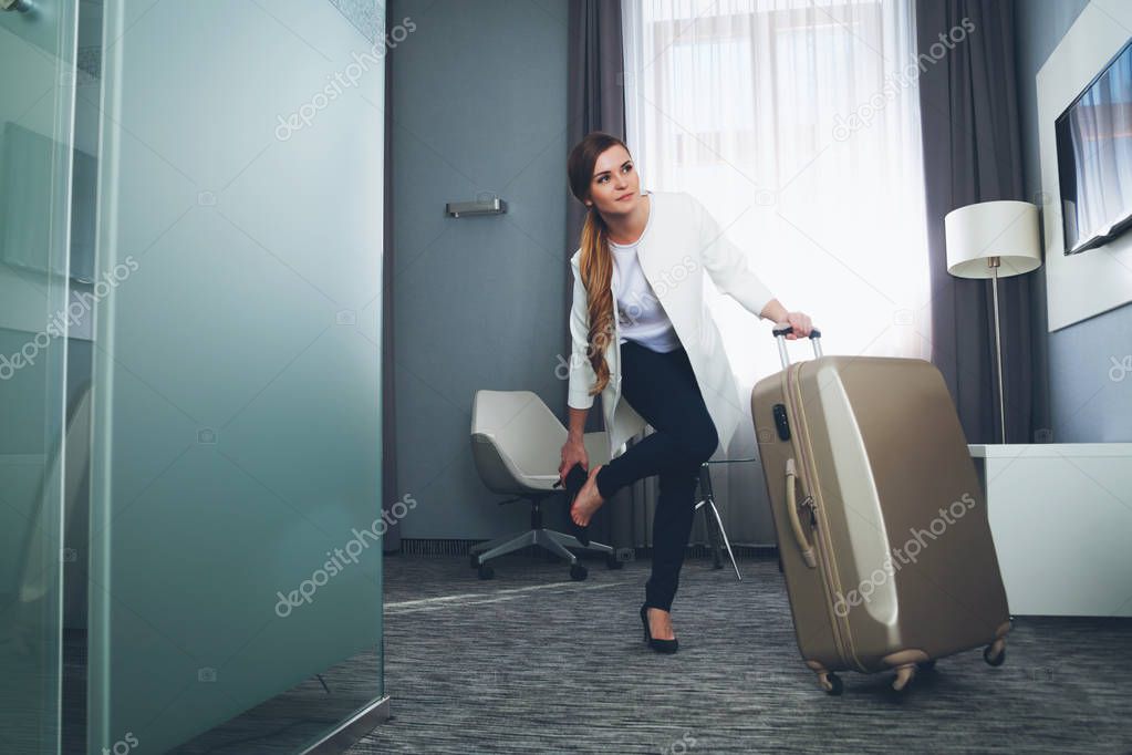 Woman pulling suitcase in modern hotel room