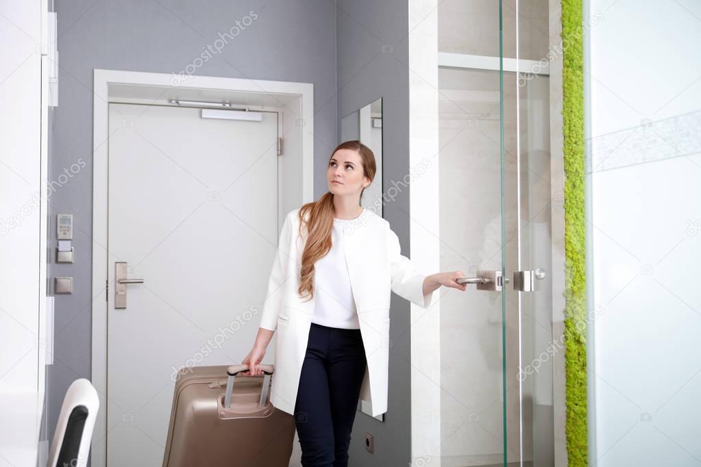 Woman pulling suitcase in modern hotel room