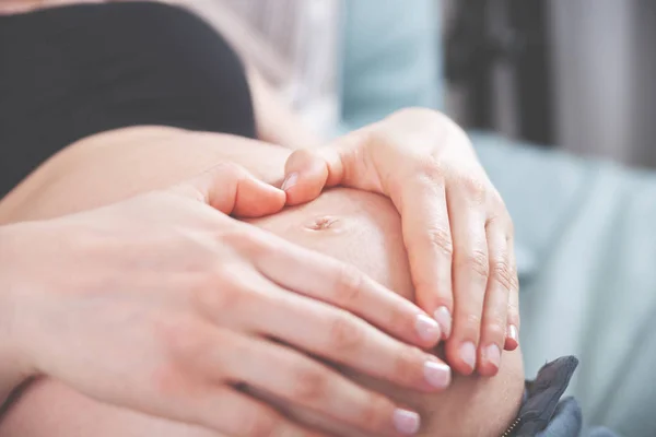 Schwangere hält zu Hause Hände in Herzform am Bauch — Stockfoto