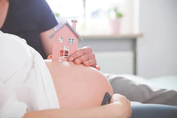 Nahaufnahme von Schwangerschaftsbauch mit kleinem Haus, Konzept von neuem Zuhause und Familie — Stockfoto