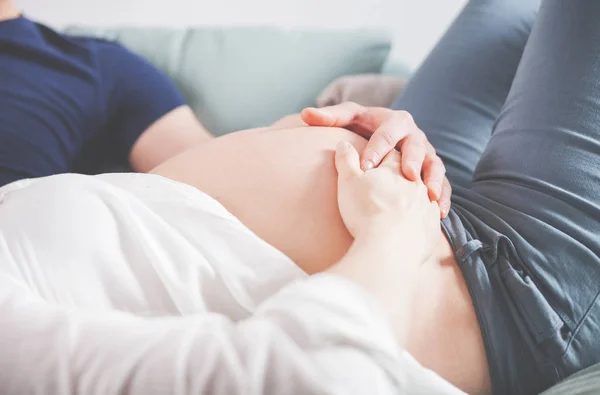 Belly terhes nő ül a kanapén, otthon — Stock Fotó