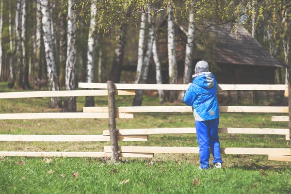 Kleiner Junge im Vorfrühling auf Zaun in Bauernhof — Stockfoto