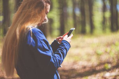Parkta yürüyüş sırasında cep telefonu kullanan kadın