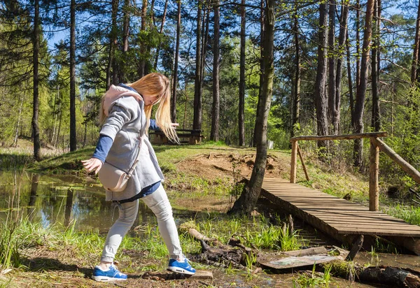 Mulher andando na floresta perto do lago e ponte — Fotografia de Stock