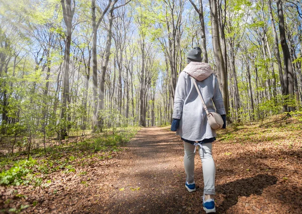 Молода жінка йде сама в ранньому весняному лісі — стокове фото