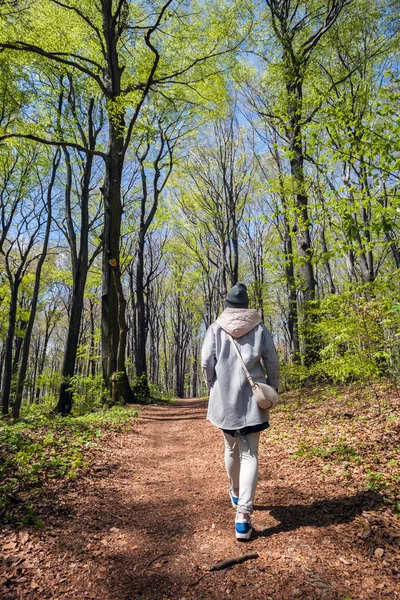 Jovem mulher caminhando sozinha no início da primavera floresta — Fotografia de Stock