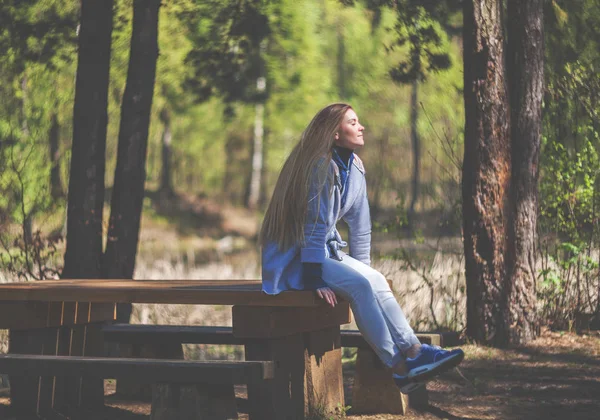 Mujer disfrutando del sol sentado en el banco en el parque —  Fotos de Stock