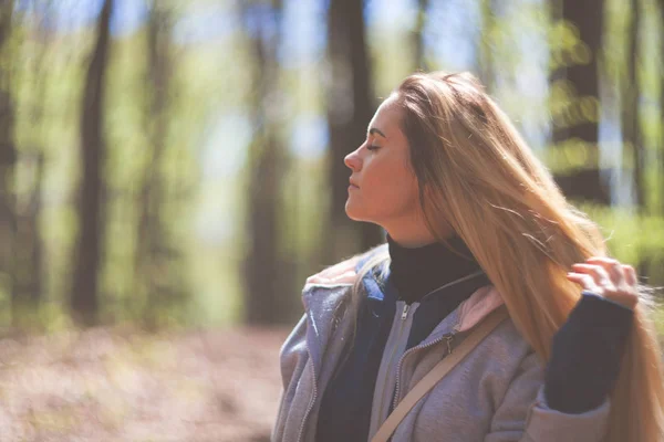 Jonge vrouw genieten van natuur tijdens zonnige dag in voorjaar park — Stockfoto