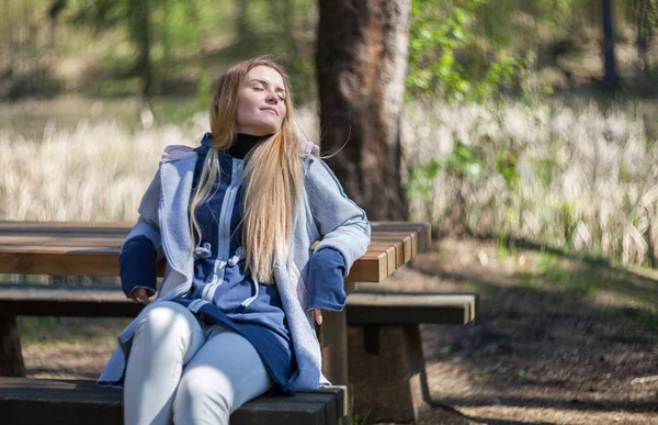 Donna che si gode il sole seduta sulla panchina nel parco — Foto Stock