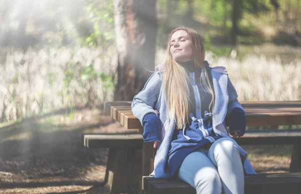 公園のベンチの上に座って太陽を楽しむ女性 — ストック写真