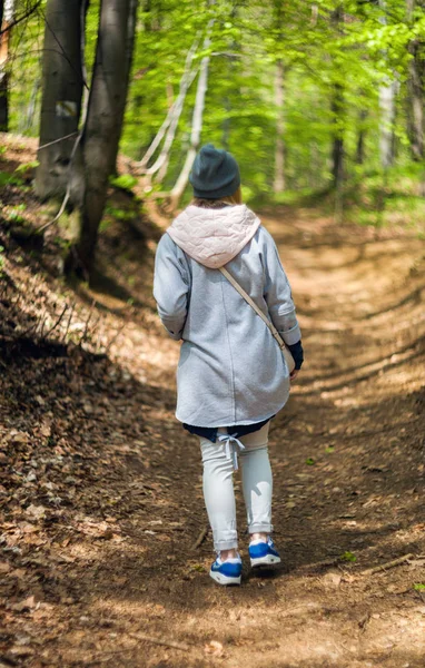 Junge Frau allein im Frühjahrswald unterwegs — Stockfoto