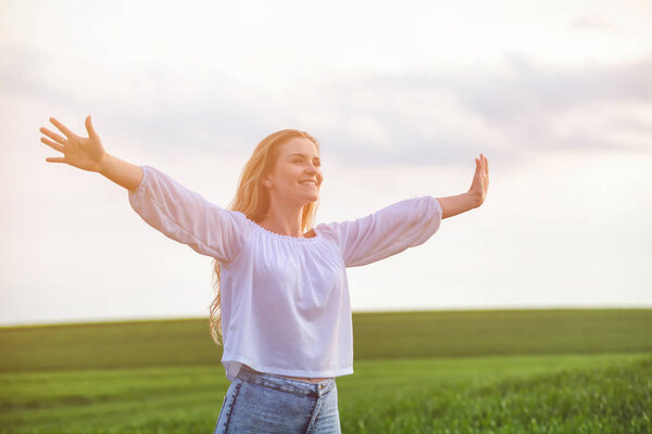 Happy smiling woman in green field at sunny day