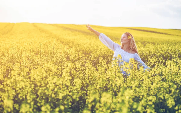 Mulher sorridente no campo de colza amarelo no dia ensolarado — Fotografia de Stock