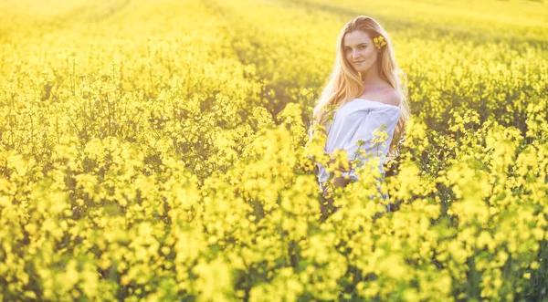 Mulher sorridente no campo de colza amarelo no dia ensolarado — Fotografia de Stock