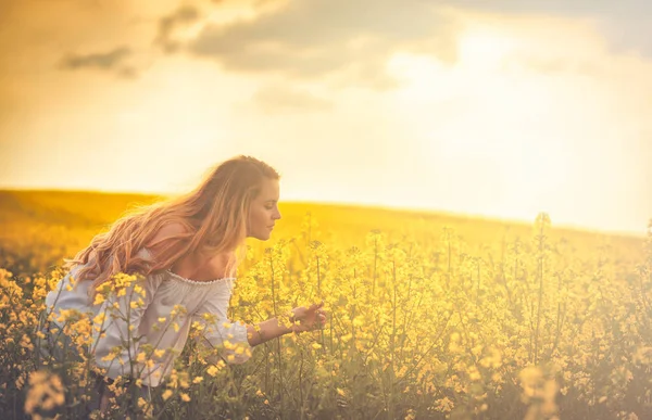Mujer sonriente en campo de colza amarilla al atardecer —  Fotos de Stock