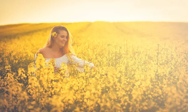 Улыбающаяся женщина на желтом рапсовом поле на закате — стоковое фото