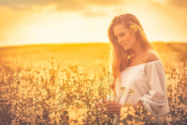 Mulher sorridente no campo de colza amarelo ao pôr do sol — Fotografia de Stock