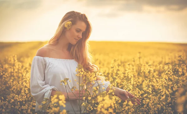 Usmívající se žena v žlutou řepkové pole při západu slunce — Stock fotografie