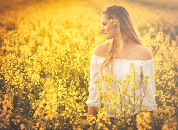 Улыбающаяся женщина на желтом рапсовом поле на закате — стоковое фото