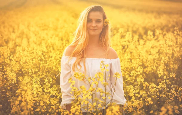 Gün batımında sarı kolza tohumu alanındaki gülümseyen kadın