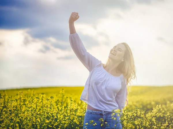 Mujer sonriente en concepto de éxito de campo de colza amarilla — Foto de Stock