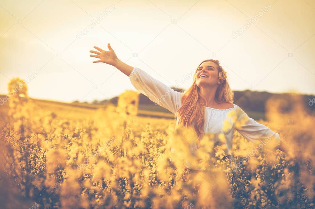 Happy smiling woman in yellow rapeseed field at sunset freedom concept