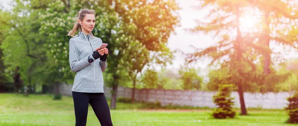 Athletic woman before start running setting up her smart phone app