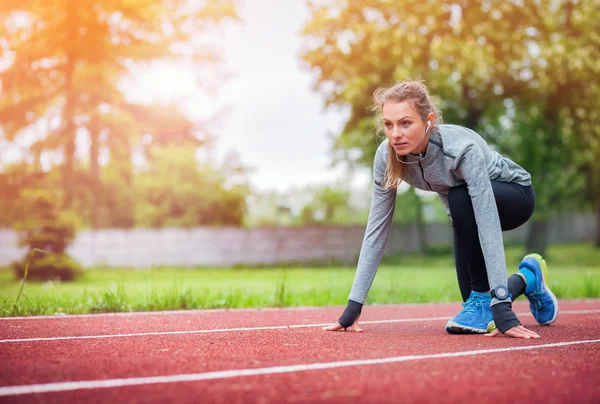 Mujer atlética en pista de correr preparándose para comenzar — Foto de Stock