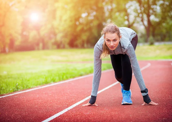 Mujer atlética en pista de correr preparándose para comenzar — Foto de Stock