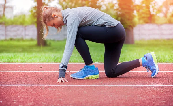 Mujer atlética en pista de correr preparándose para comenzar — Foto de Stock