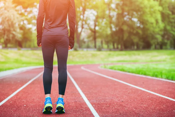Athletic woman on running track getting ready to start run back view — Stock Photo, Image