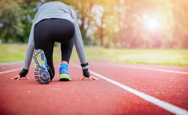 Mulher atlética em pista de corrida se preparando para começar a correr para trás vista — Fotografia de Stock