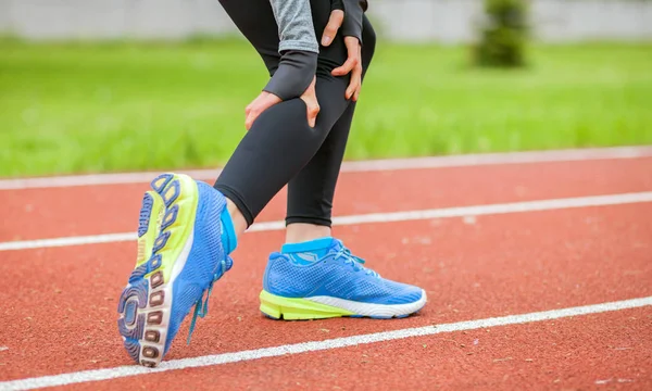 Mulher atlética na pista de corrida tem cãibra de bezerro e tocar perna ferida — Fotografia de Stock