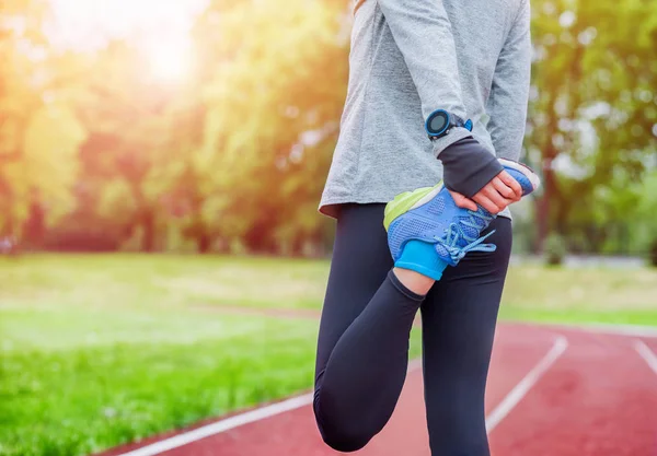 Mujer atlética en pista de atletismo estiramiento antes de entrenar accesorios de fitness — Foto de Stock