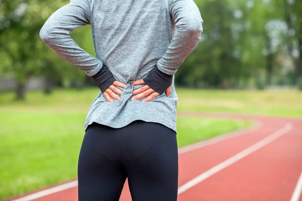 Kobieta lekkoatletycznego na bieżnię dotykając boli z powrotem bolesnej kontuzji — Zdjęcie stockowe