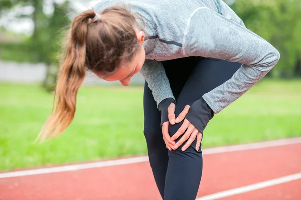 Mujer atlética en pista de correr tocando pierna herida con lesión de rodilla — Foto de Stock