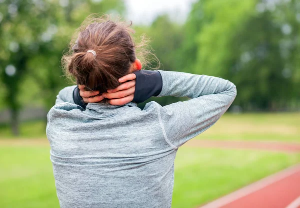 Спортивная женщина на беговой дорожке трогает больную шею с болезненной травмой — стоковое фото